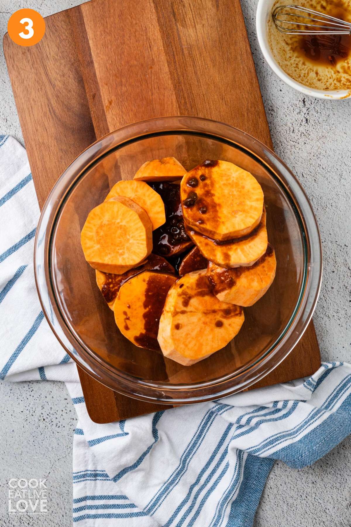 Balsamic and miso mixture poured over sliced sweet potato rounds in a glass bowl.