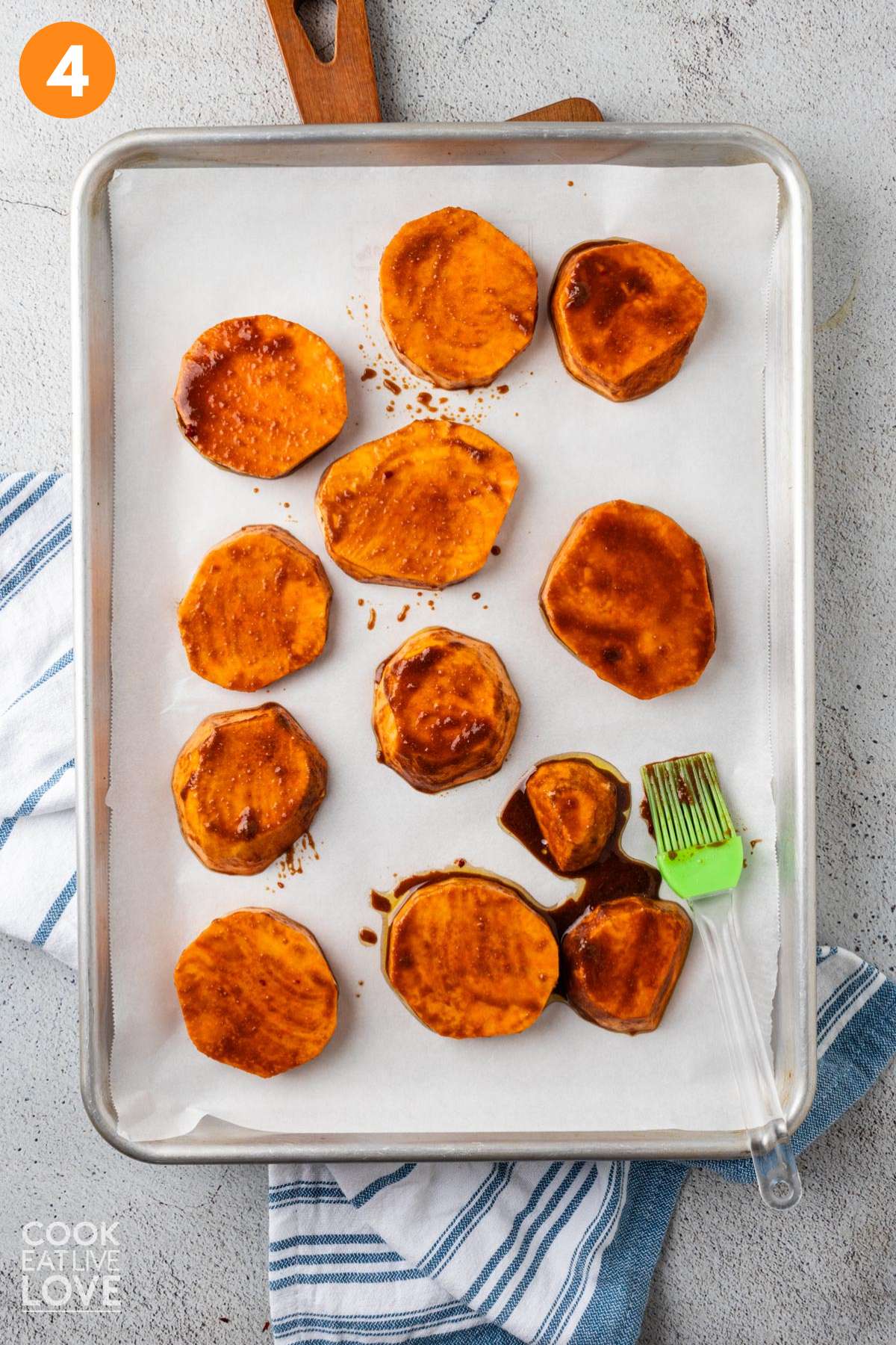 Balsamic miso sweet potato slices laid out on a baking tray lined with parchment.