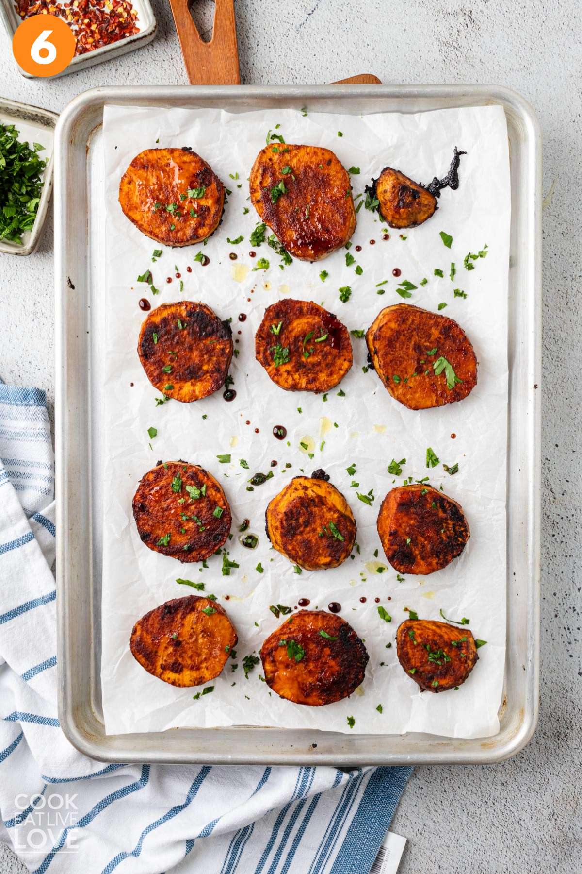 Roasted sweet potato slices on a baking tray sprinkled with parsley.