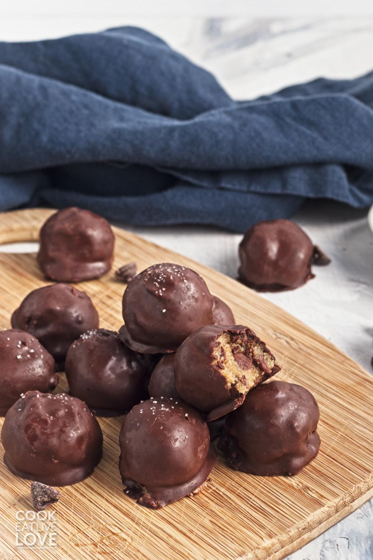 A pile of cookie dough bites on a wooden cutting board.