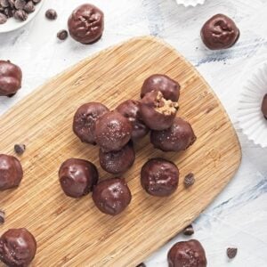 Cookie dough bites stacked on top of each other on a wooden baord on the table.