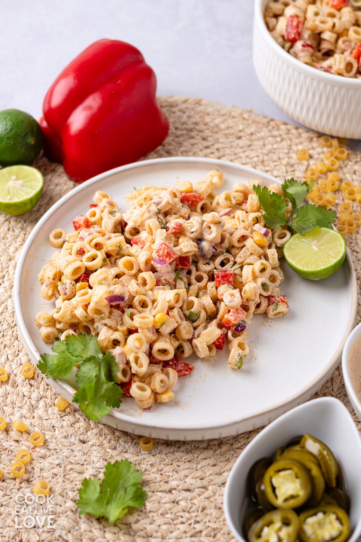 A plate of Mexican macaroni salad with lime half and cilantro.