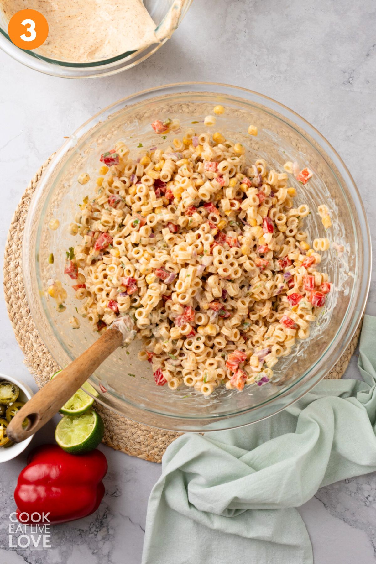 Dressing mixed with the pasta and vegetables in a bowl.