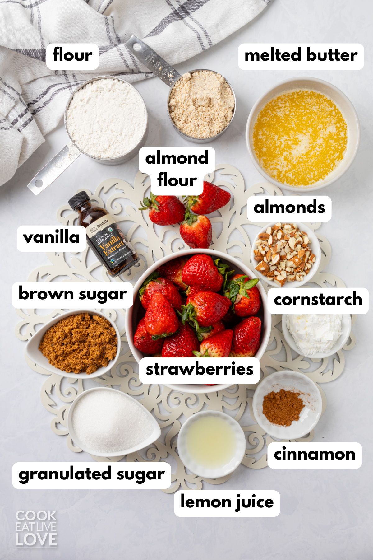Ingredients to make strawberry crumble on a table with labels to identify each one.