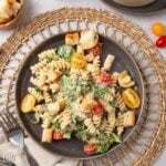 A plate of Caesar pasta salad on a woven mat on the table.