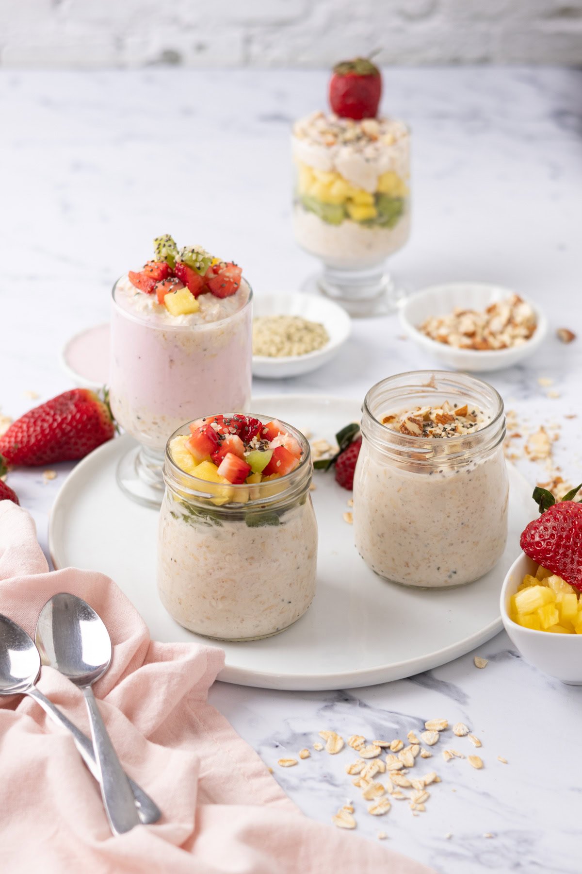 Greek yogurt overnight oats on a plate topped with nuts and fresh fruit.