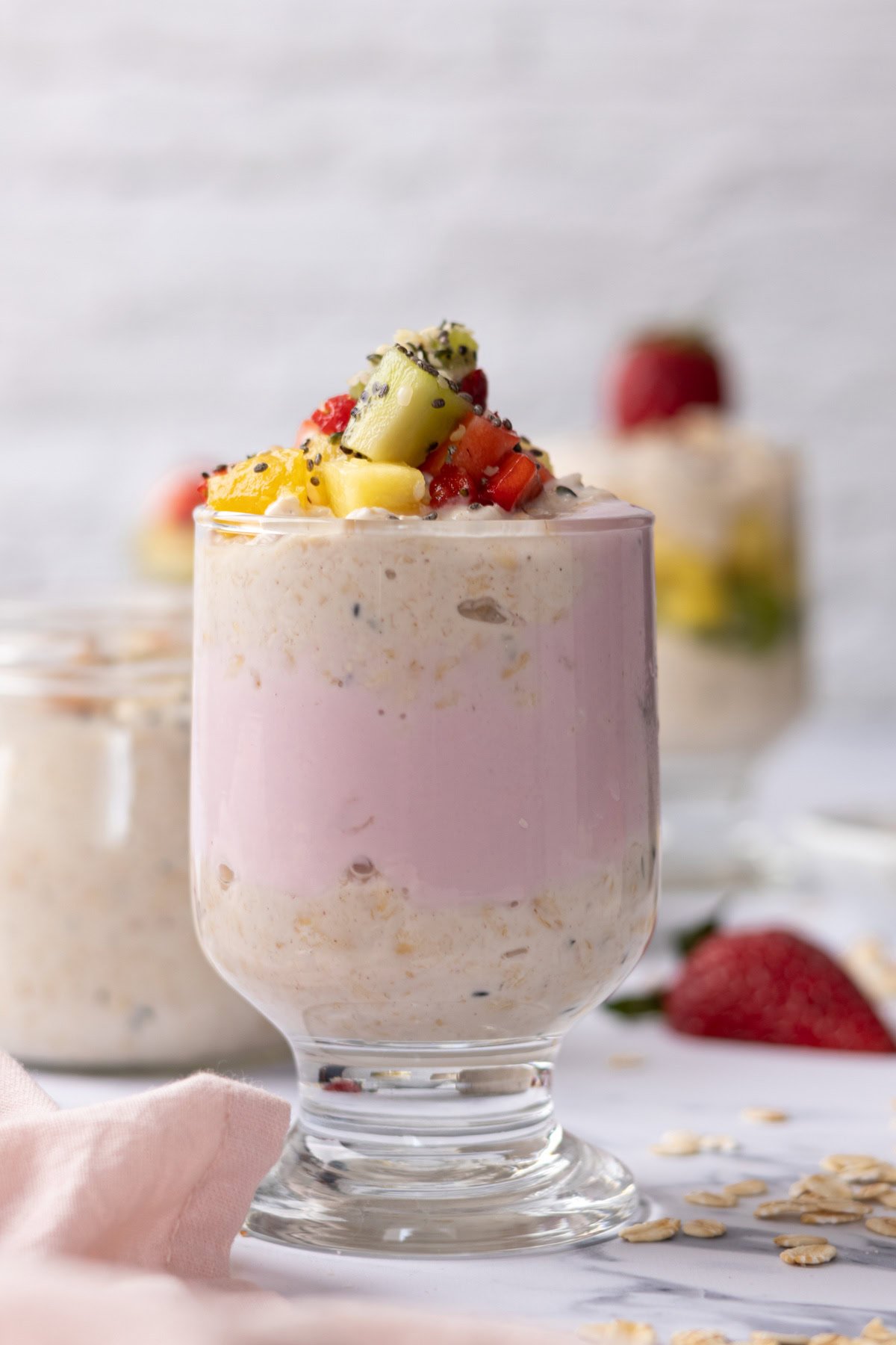 Greek yogurt overnight oats layered in a glass with strawberry yogurt and fruit.