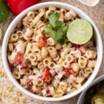 A bowl of Mexican macaroni salad garnished with a lime and cilantro.