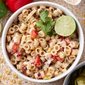 A bowl of Mexican macaroni salad garnished with a lime and cilantro.