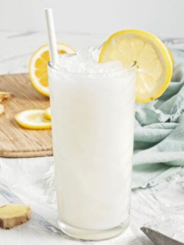 Creamy coconut lemonade in a glass over ice with lemon slices.