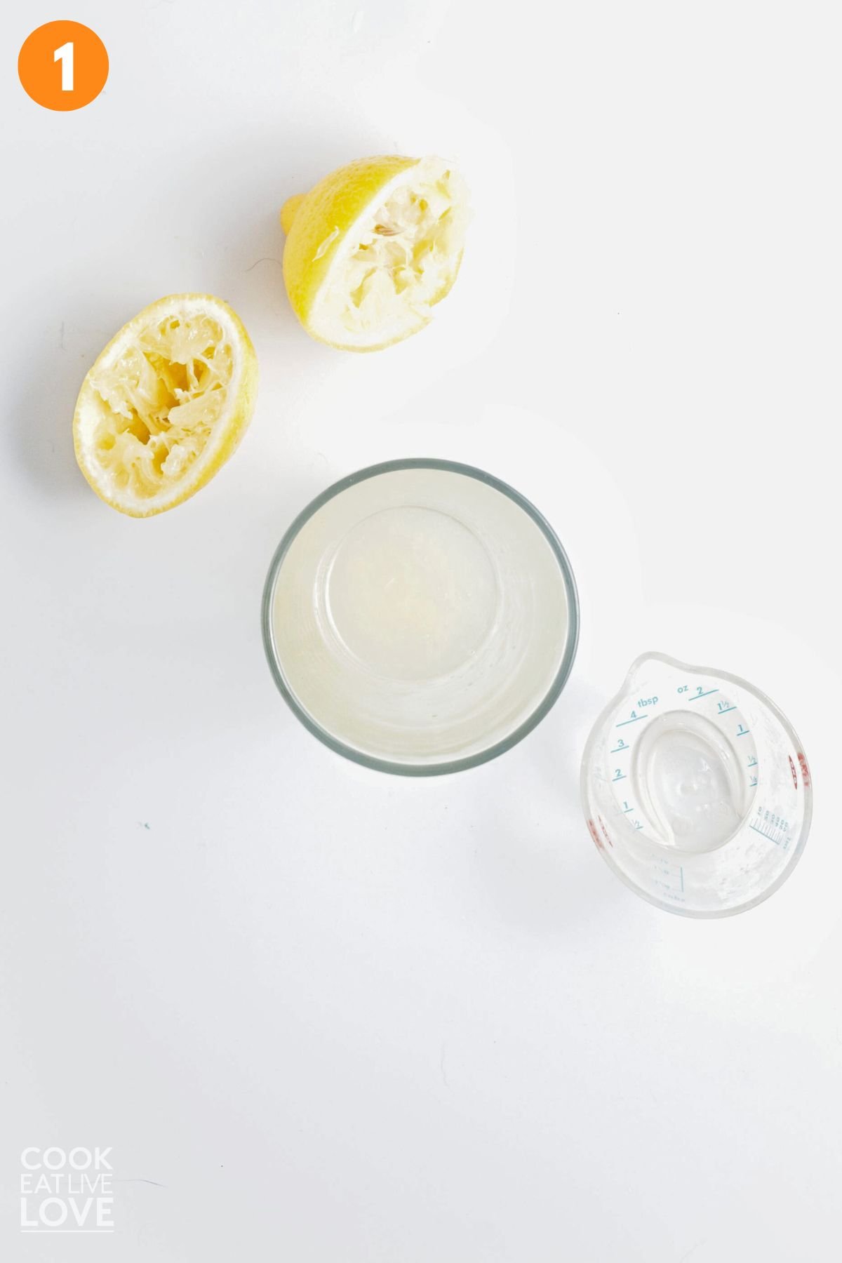 Lemon juiced into a glass with squeezed lemon halves off to the side.