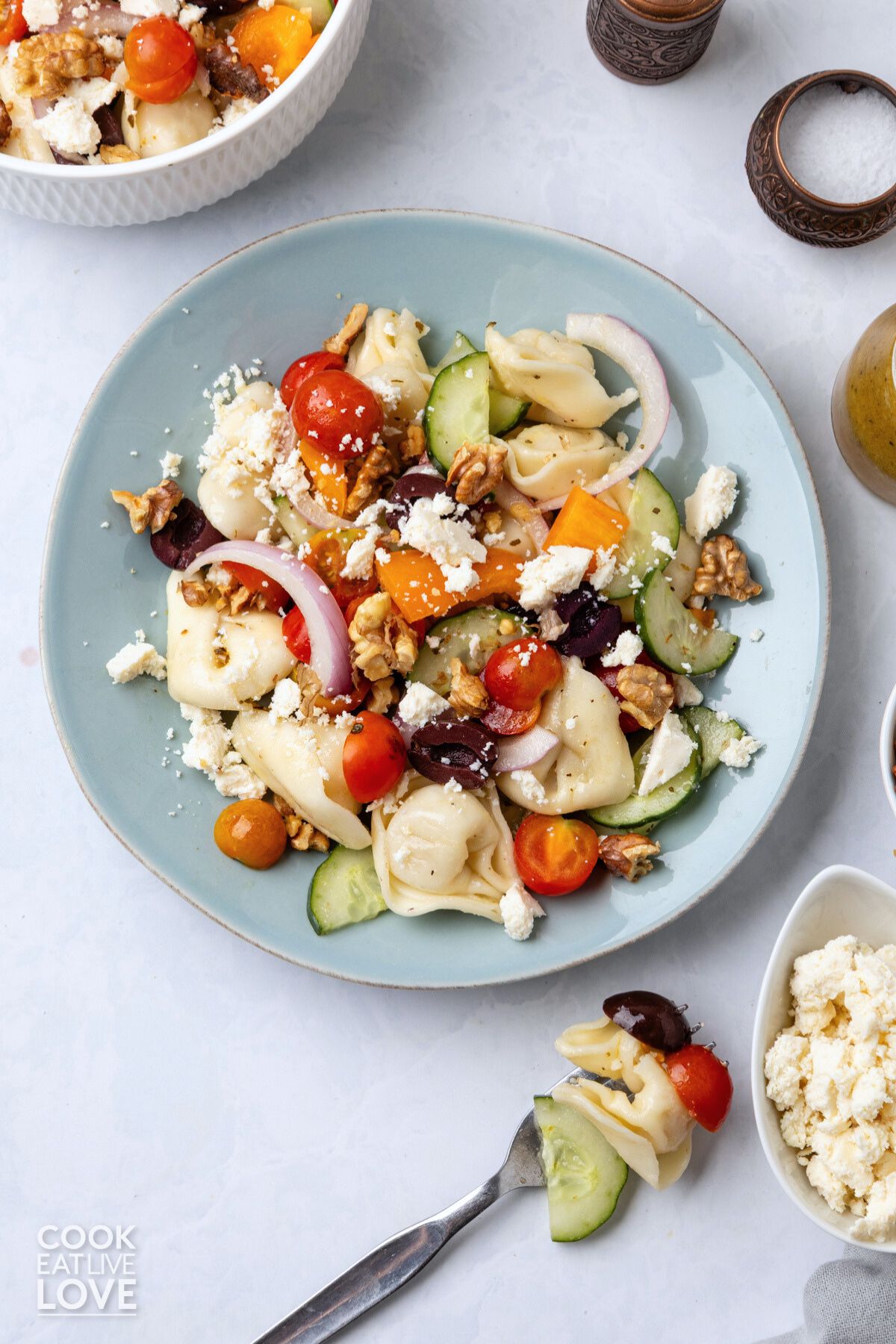 Greek tortellini salad on a blue plate garnished with feta cheese.