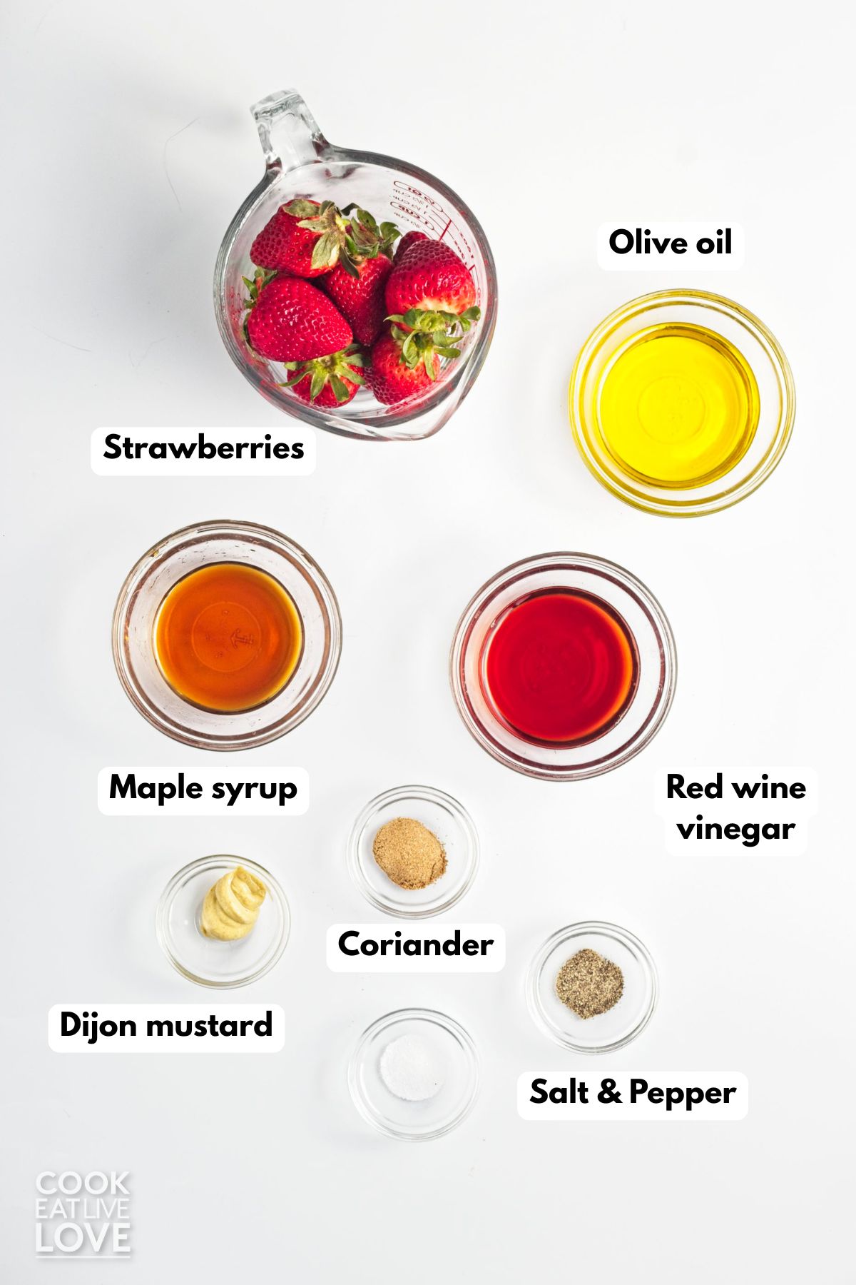 Ingredients to make strawberry salad dressing on the table with text labels identifying each one.