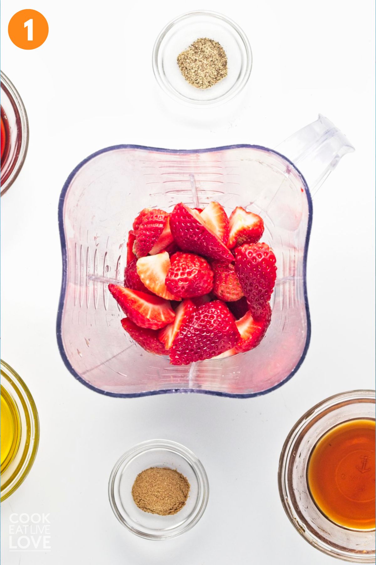 Strawberries added to a blender with the other ingredients in bowls to the side.