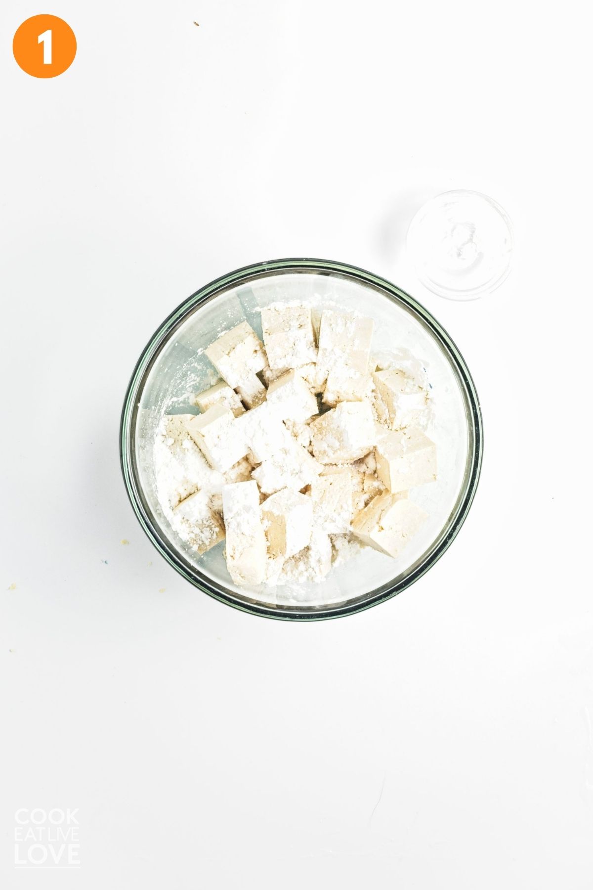 Tofu in a bowl tossed with cornstarch.