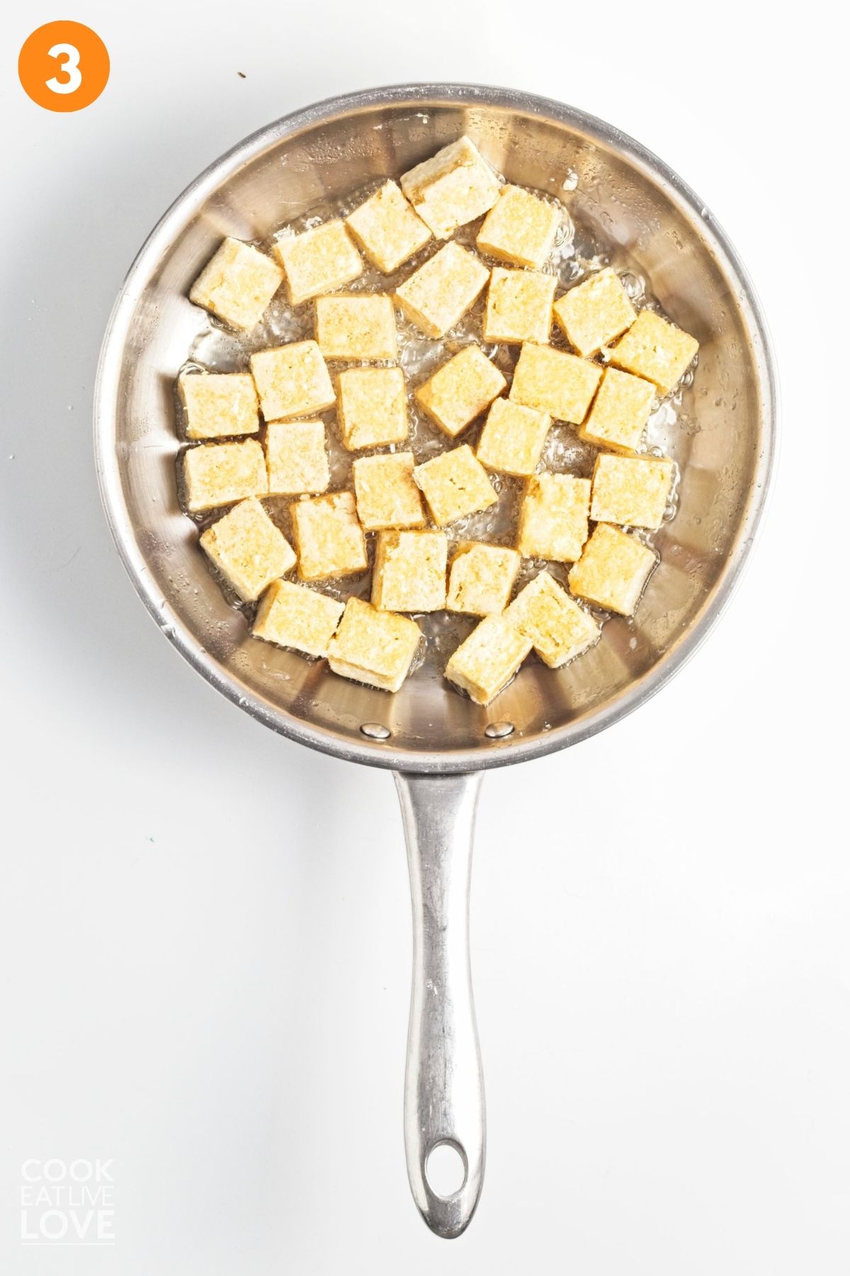 Tofu cooking a skillet.