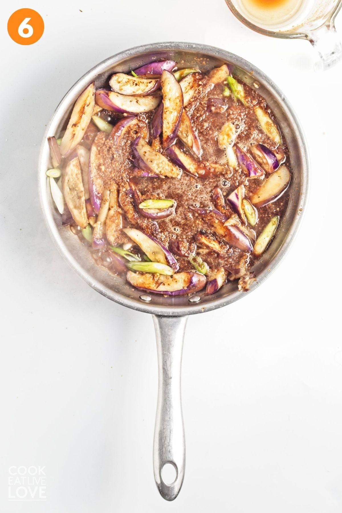 Eggplant and green onions cooked in a skillet.