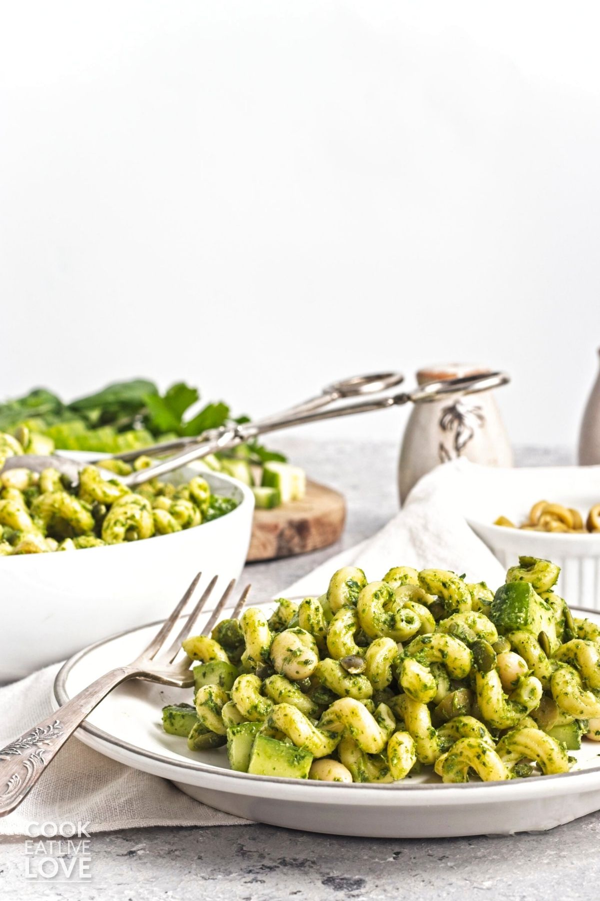 A plate of green goddess pasta salad with a bowl of more in the background.