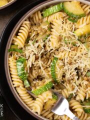 A bowl of lentil zucchini pasta with a fork resting in the side.