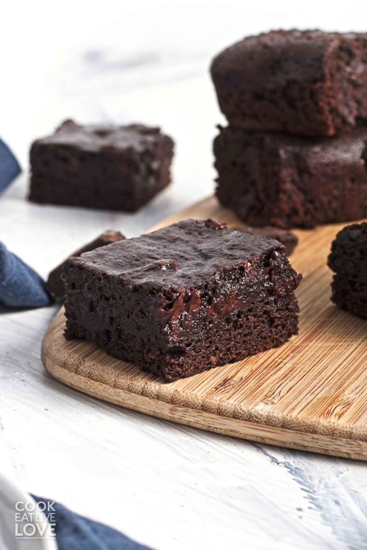 Zucchini brownies on a wooden platter and directly on a white surface.