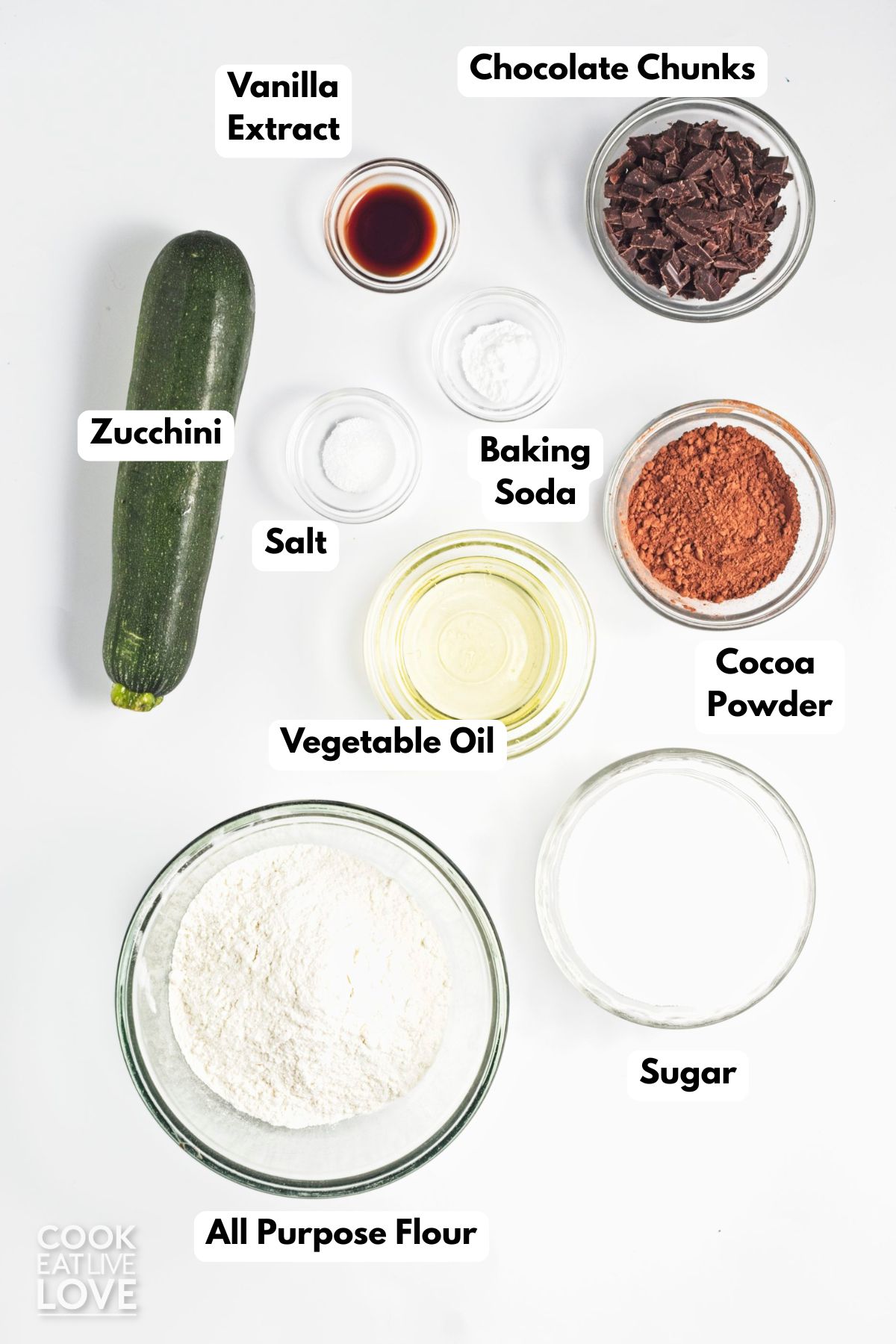Ingredients to make vegan zucchini brownies in bowls with labels to identify each.
