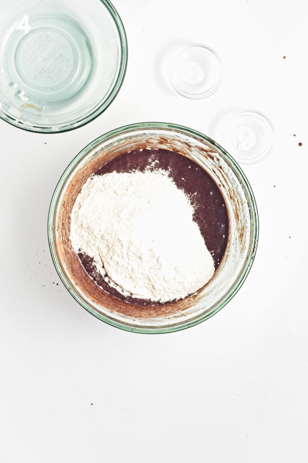 Flour added to the bowl of vegan zucchini brownie batter.