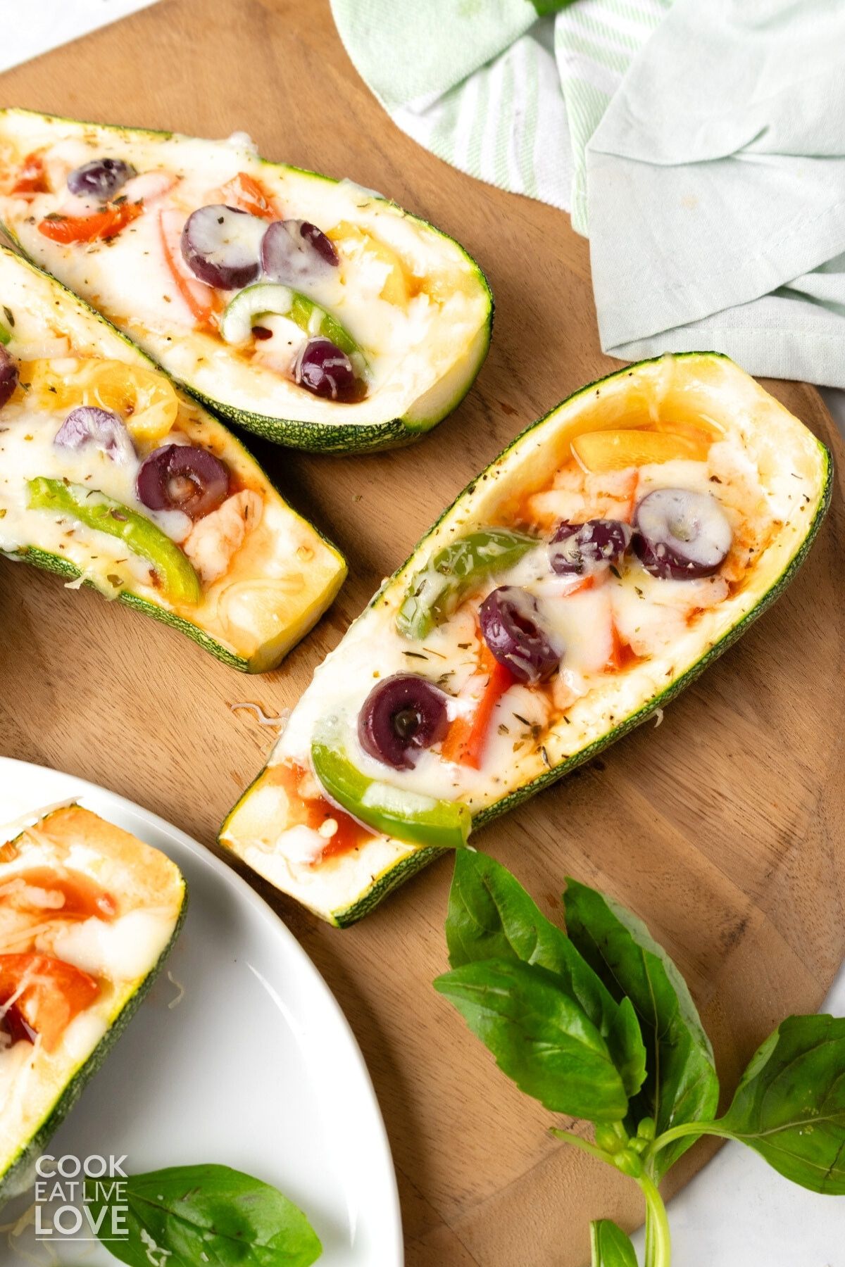 Zucchini pizza boats laid out on a wooden pizza board.