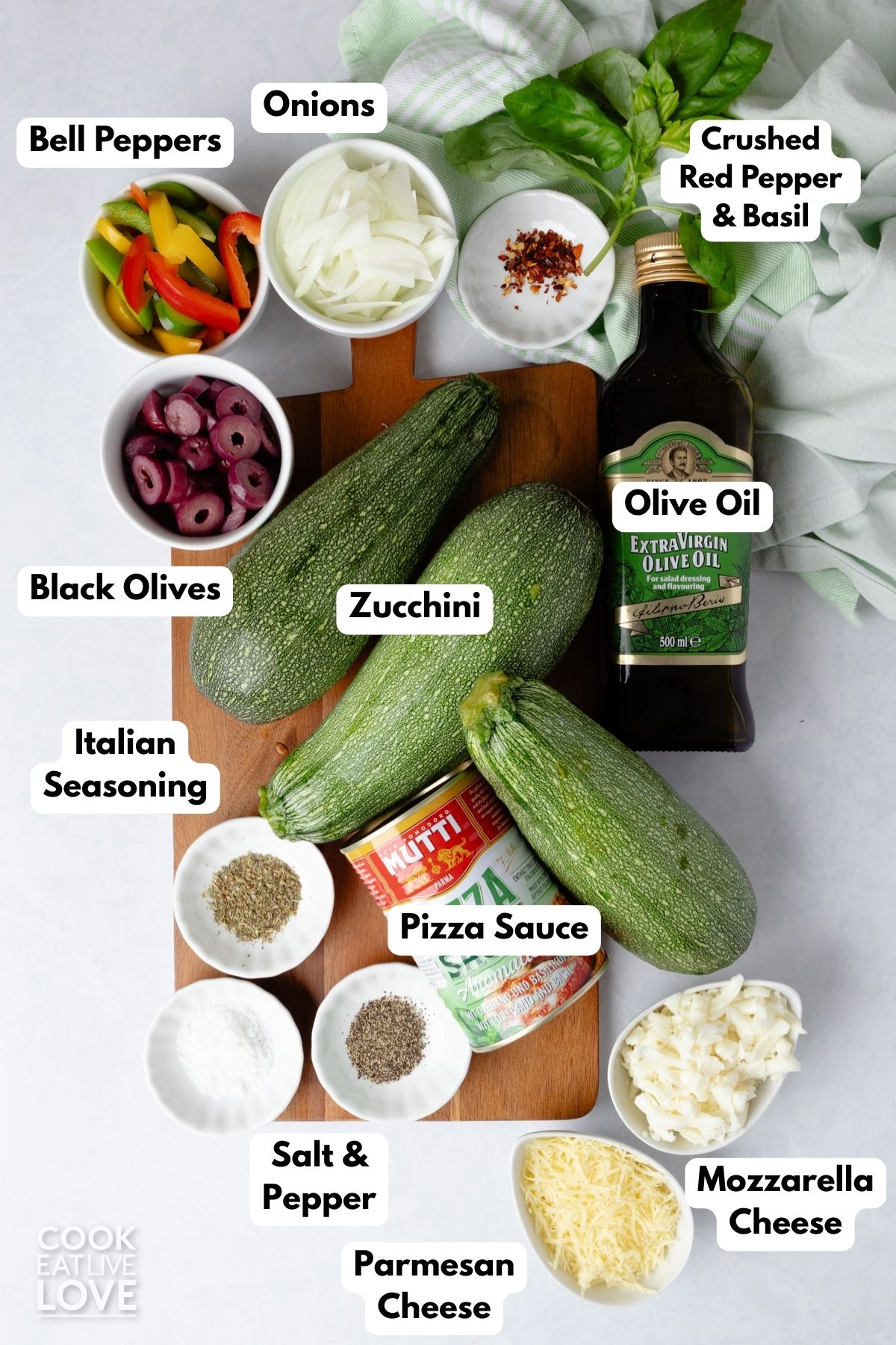 Ingredients to make zucchini pizza boats on a surface with text labels to identify each one. 