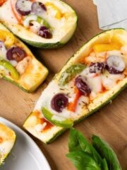 Zucchini pizza boats on a wooden board.