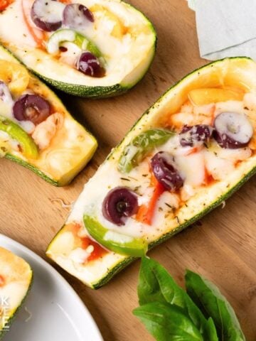 Zucchini pizza boats on a wooden board.