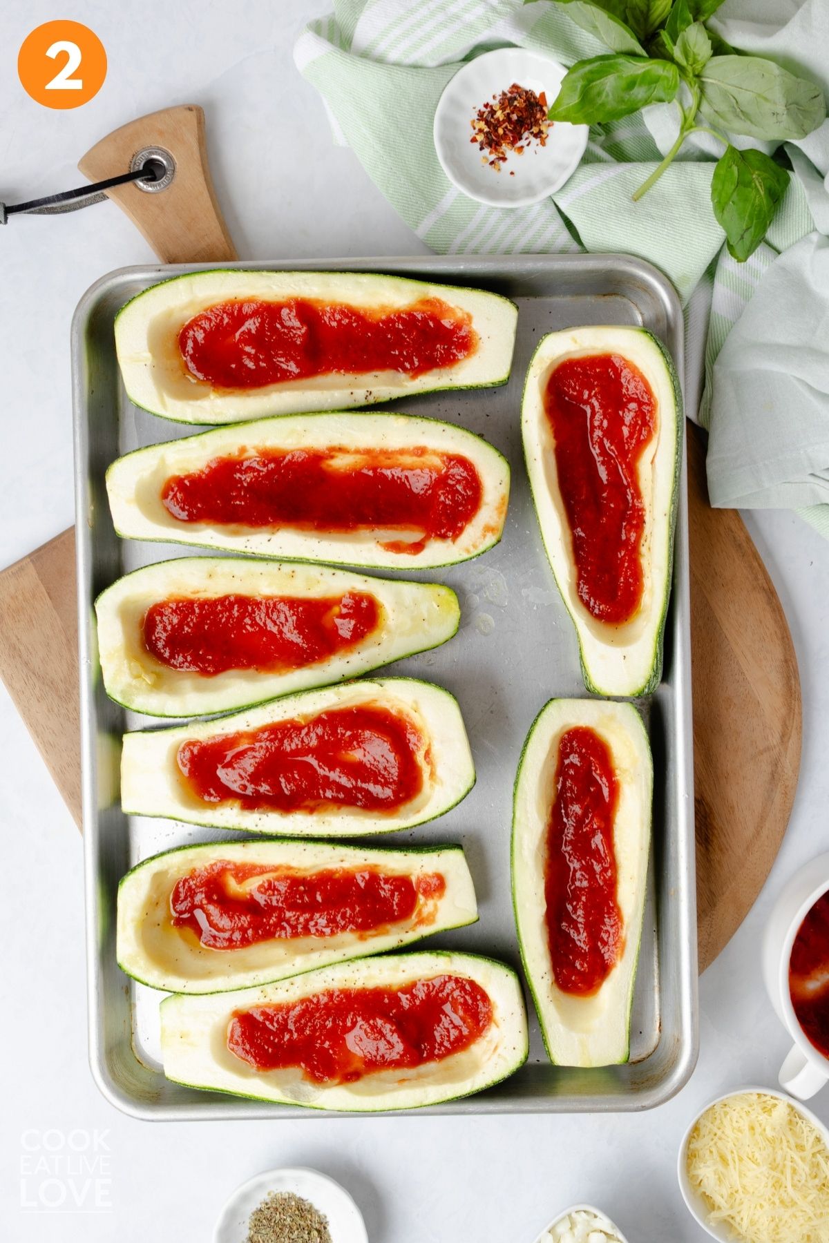 Pizza sauce added to the zucchini boats.
