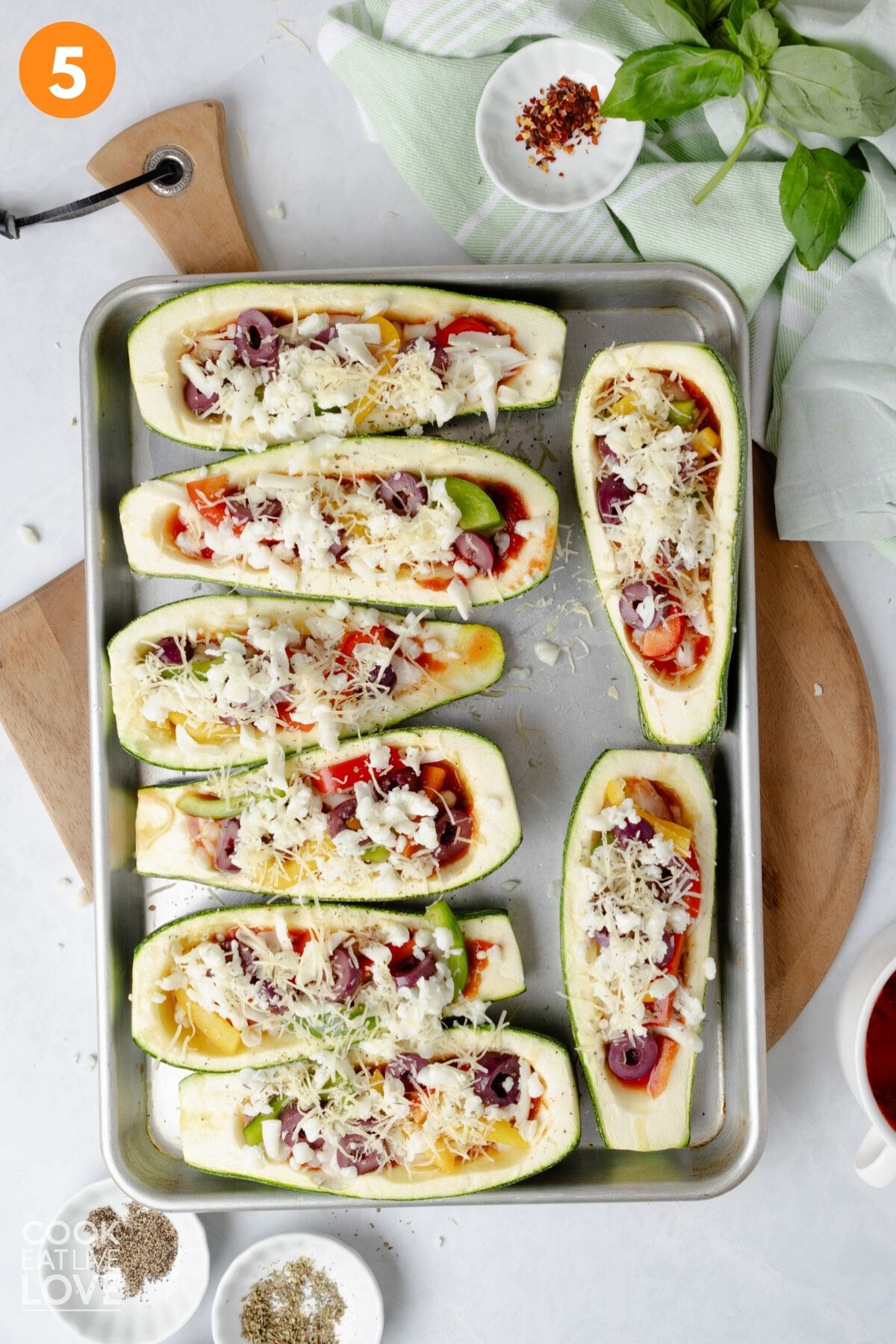 Mozzarella cheese sprinkled on top of the zucchini pizza boats.