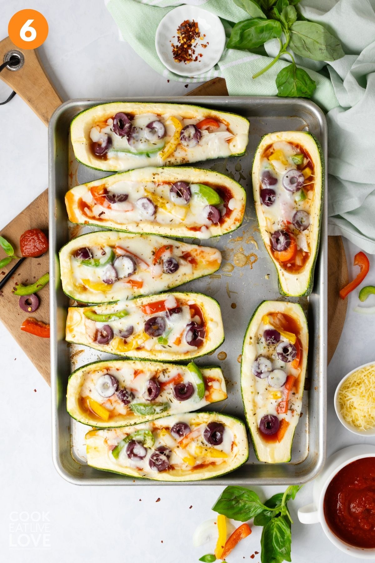 Melted cheese on top of the vegetable pizza boats laid out on a baking tray.