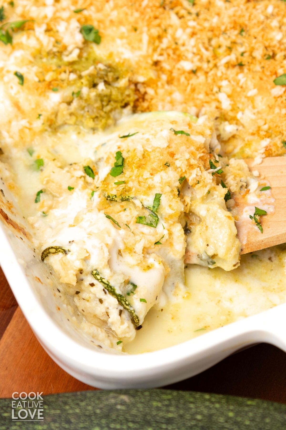 Zucchini rollatini with creamy sauce in a white baking dish.