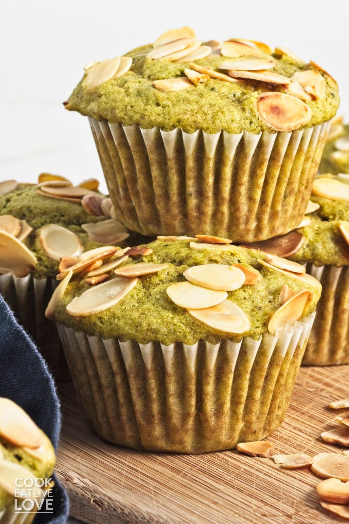 Two matcha muffins stacked on one another with more in the back. 