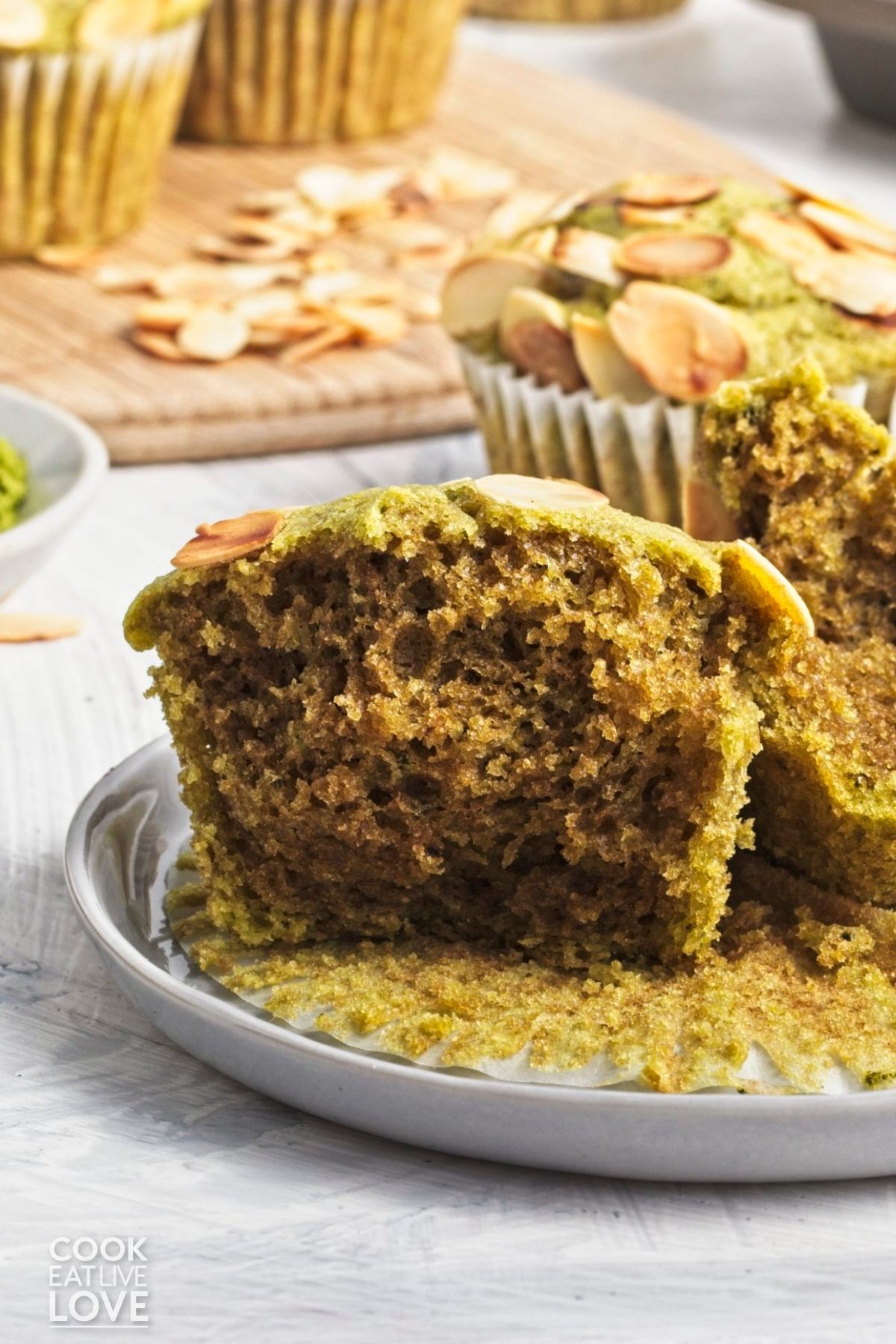 A matcha green tea muffin split in half on a plate to show the inside. 