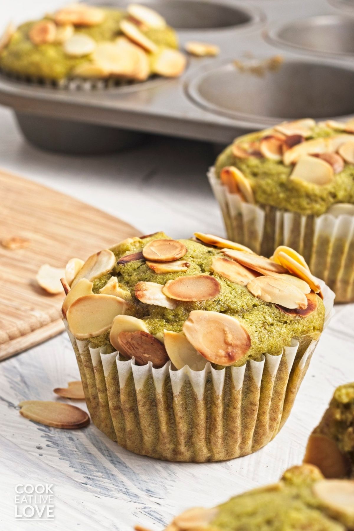 Matcha muffins on a surface with nuts sprinkled around.
