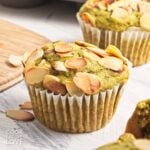A matcha muffin topped with almonds on a white surface.