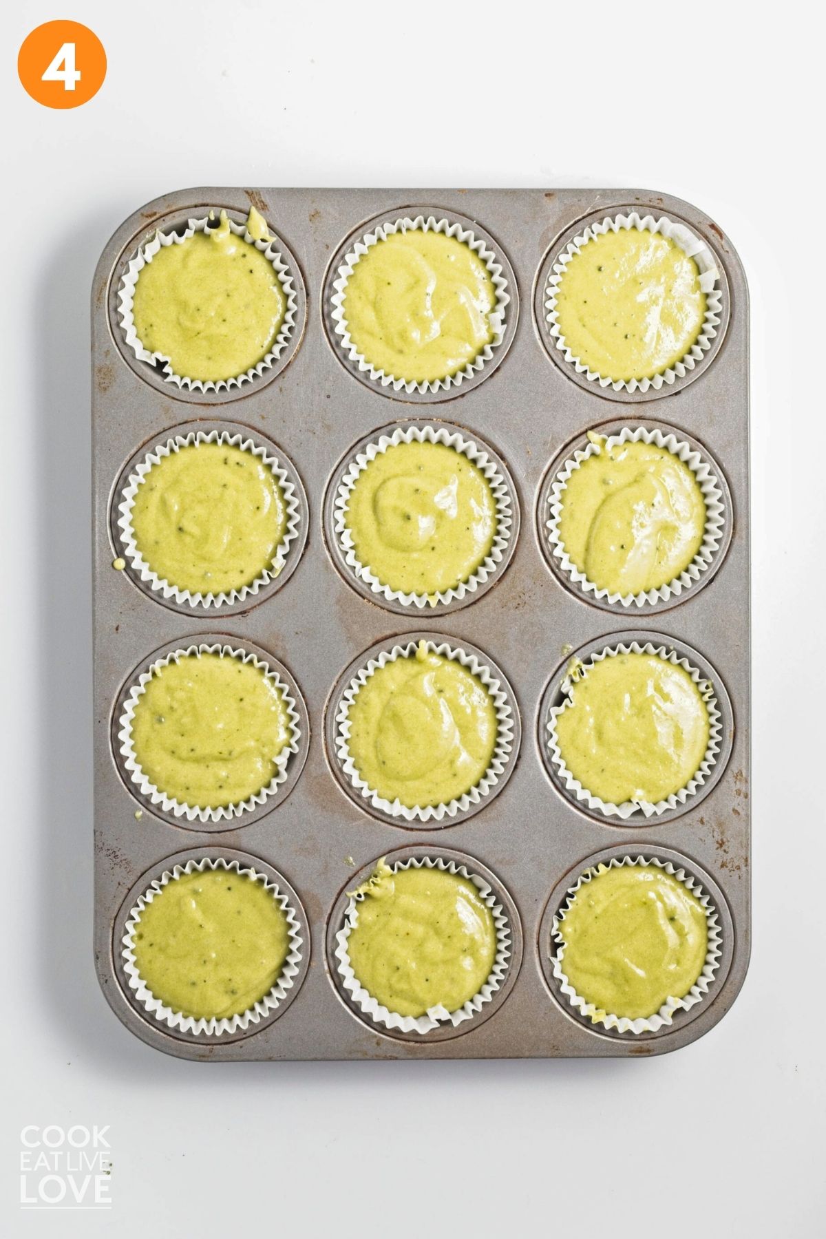 Green tea muffin batter poured into a muffin pan.