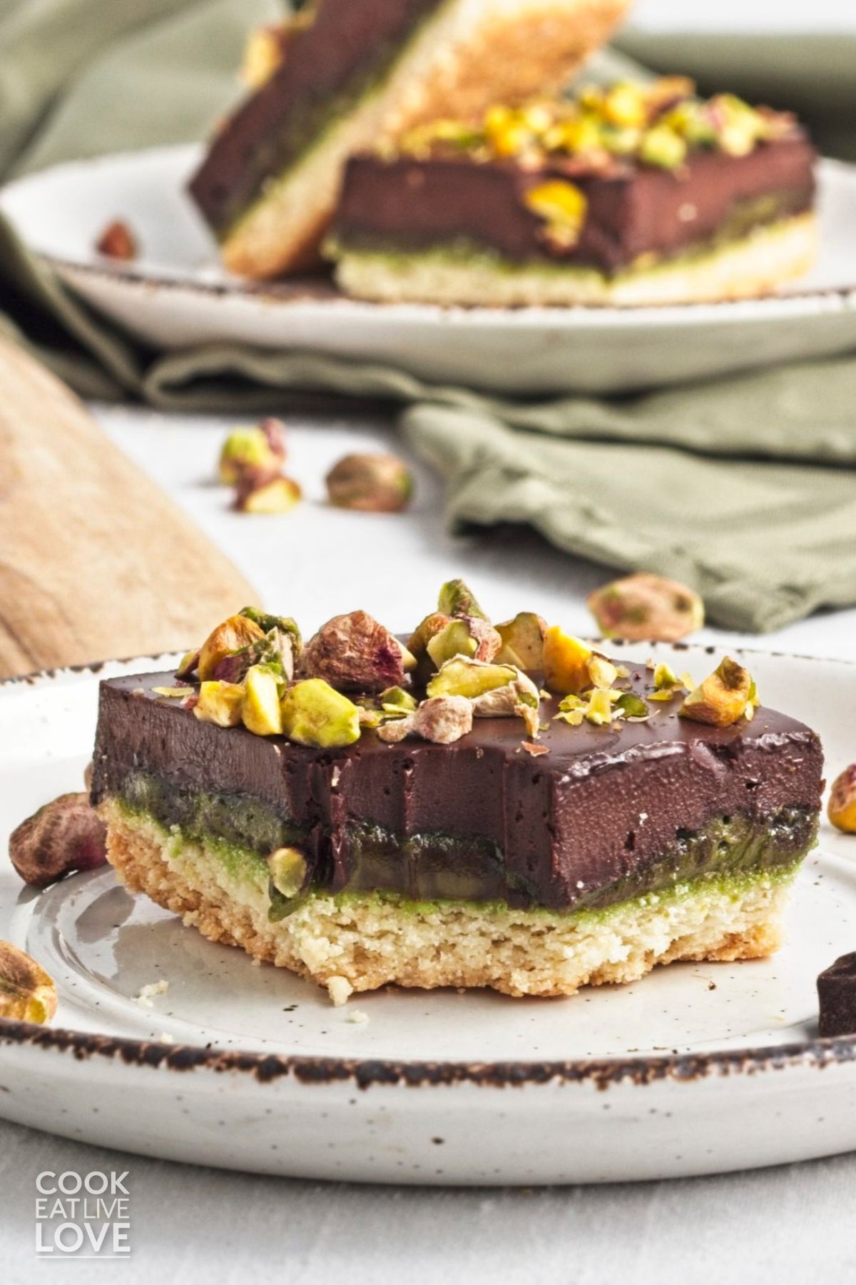 A bite taken from a pistachio bar sitting on a small plate. 