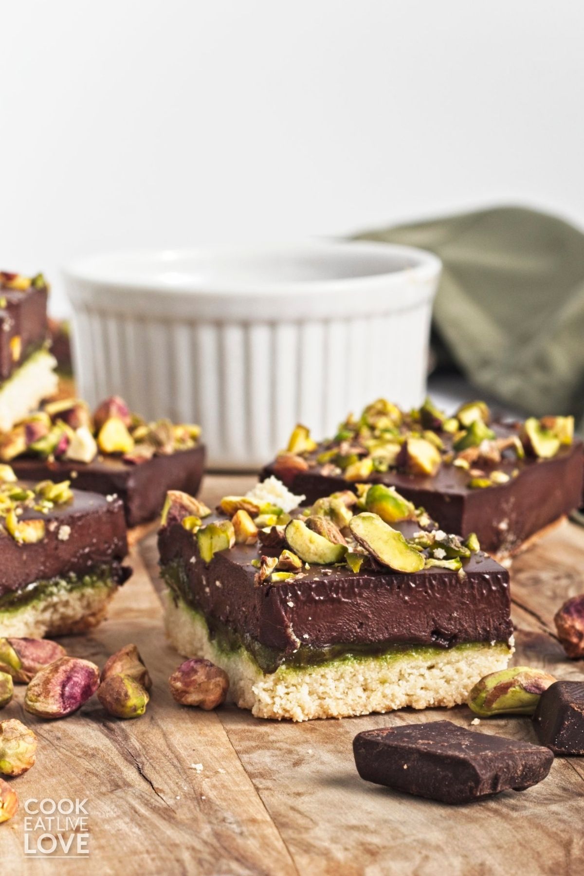 Pistachio chocolate bars cut into squares on a wooden cutting board.