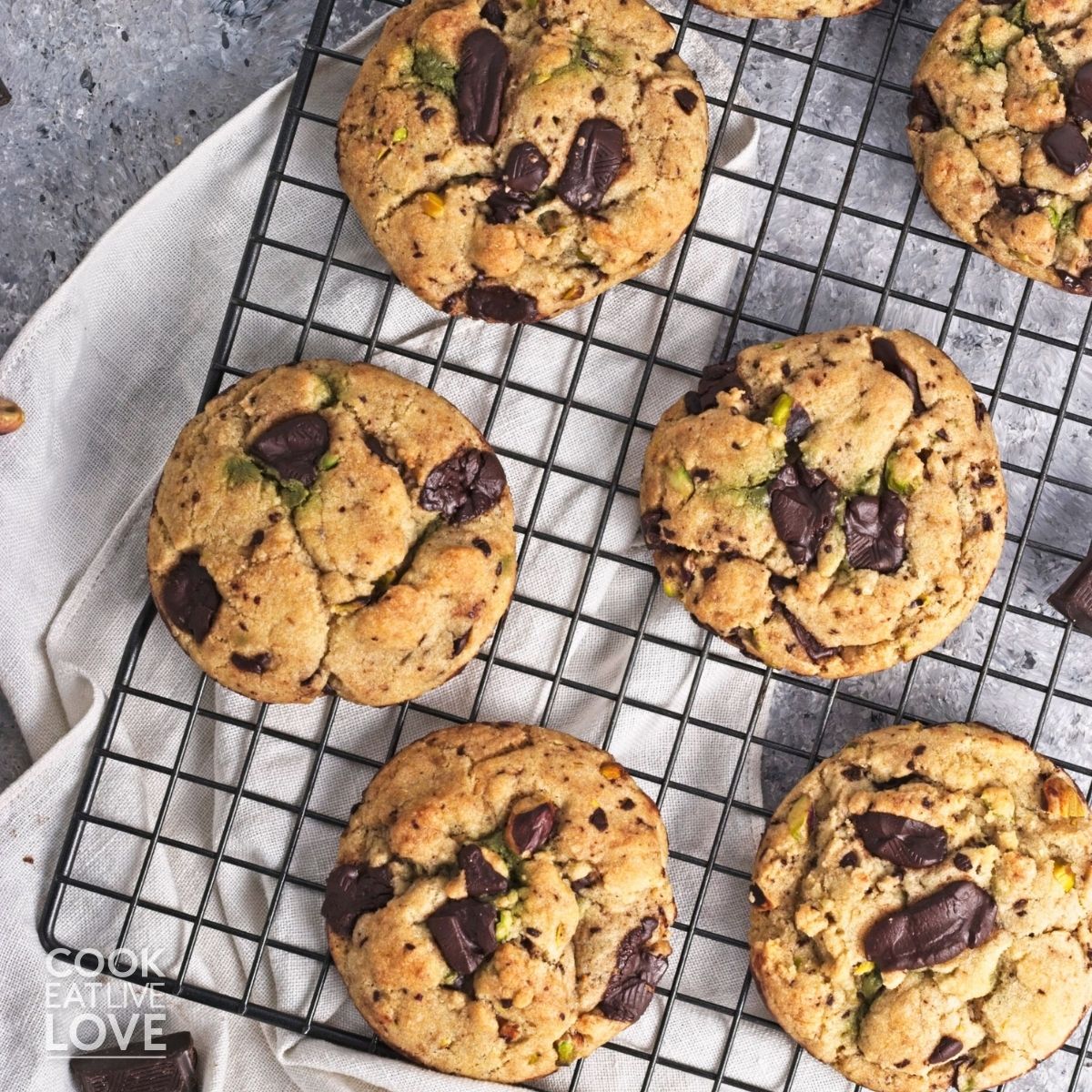 Pistachio chocolate chip cookies on a wire rack.