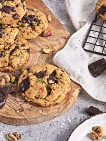 Pistachio chocolate chip cookies on a wooden platter.