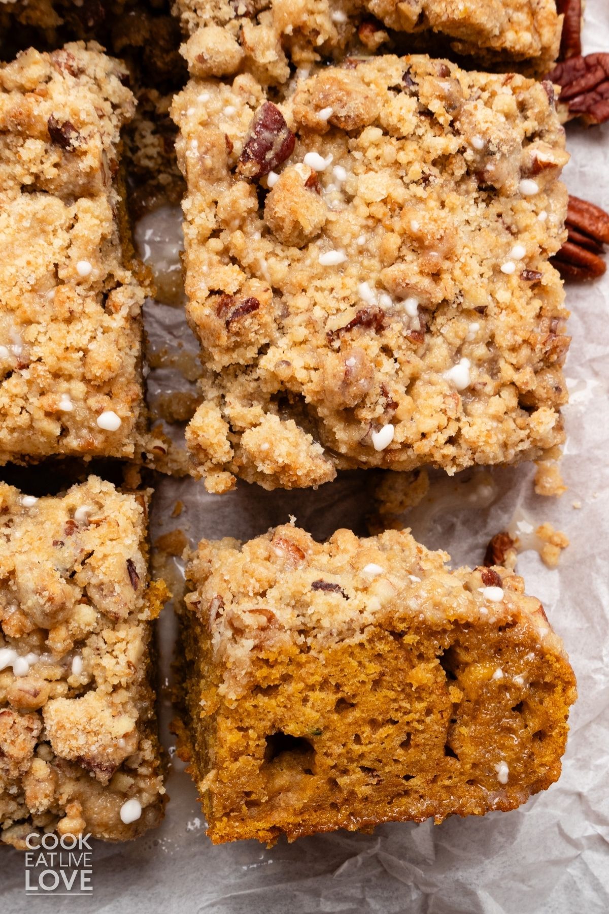 Squares of pumpkin coffee cake with one turned on it's side to show cake with streusel topping. 
