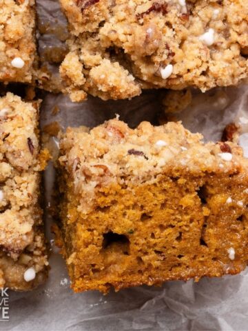 Pumpkin coffee cake cut into squares with one turned on its side to show cake and streusel topping layers.
