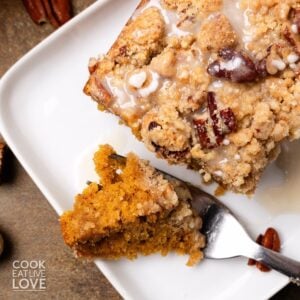 Pumpkin coffee cake served on a white plate with a bite cut to the side.