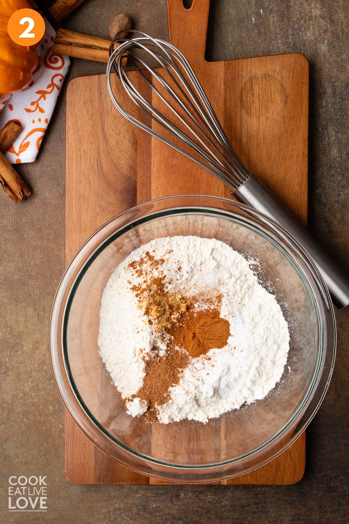 Dry ingredients added to a mixing bowl with a whisk resting to the side. 