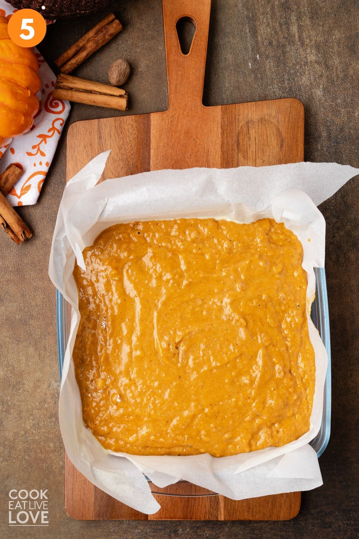 Pumpkin cake batter poured into a parchment lined baking dish. 