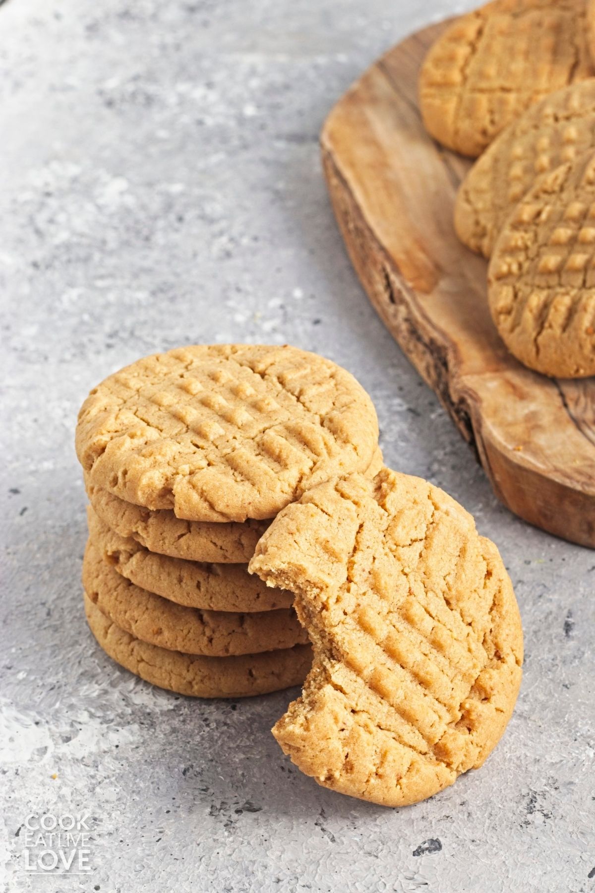 A stack of vegan peanut butter cookies with a bite missing from one leaning against it. 