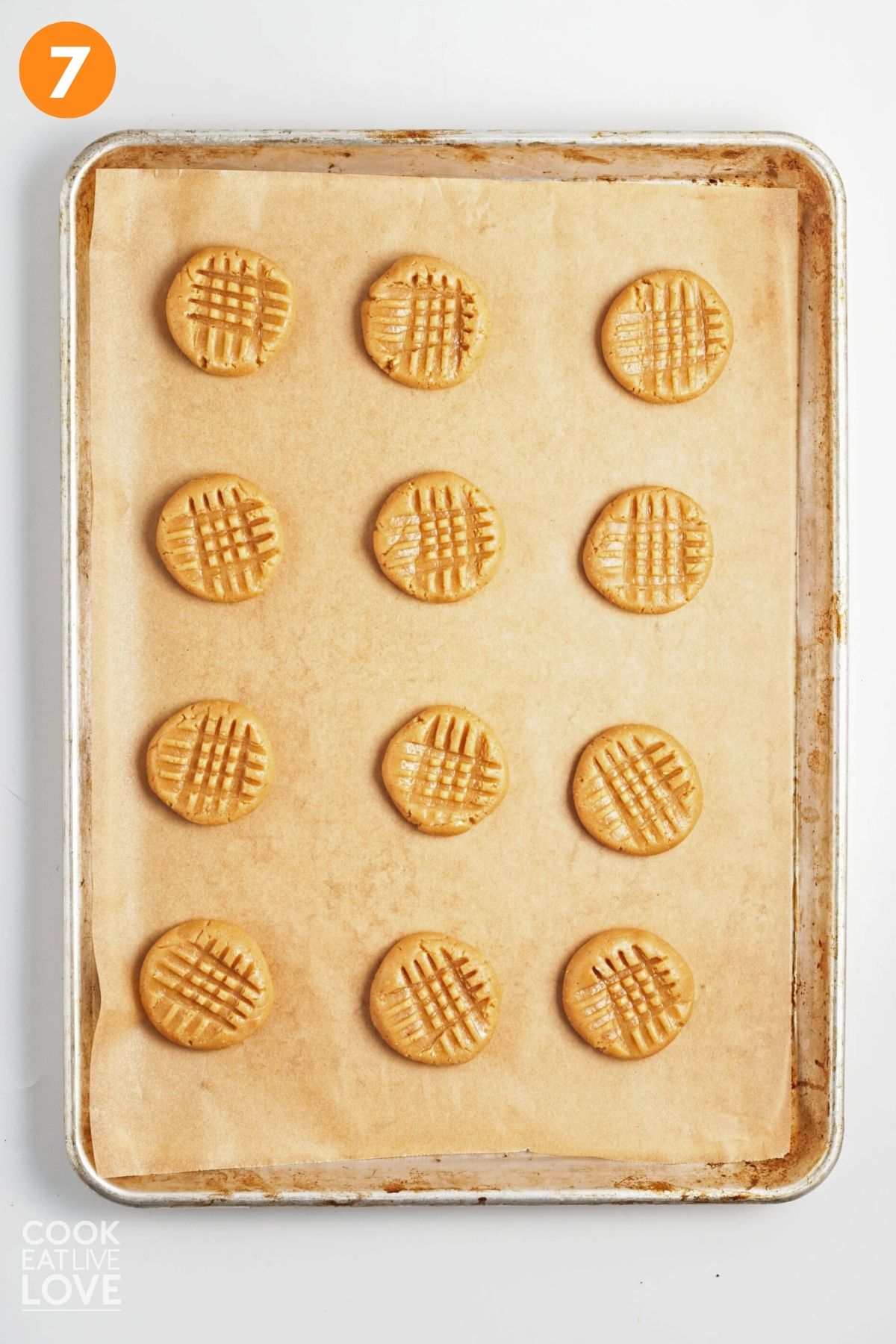 Cookie dough balls are flattened with a criss cross pattern on top. 